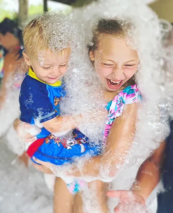 Toddler and sister laughing together in the foam
